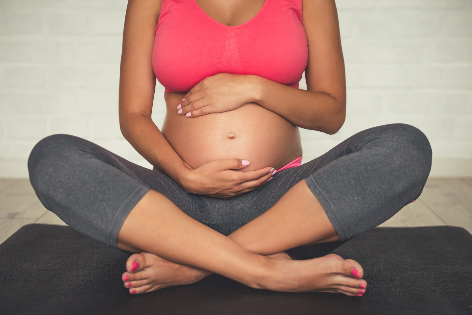 Pregnant-woman-sitting-cross-legged-on-yoga-mat