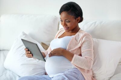 Pregnant woman on couch holding a tablet