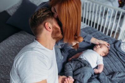 Young parents sitting on a bed. Sex after baby