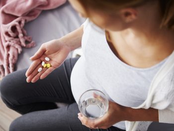 Pregnant woman looking at several prenatal vitamins in her hand