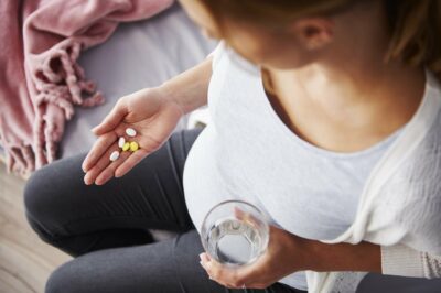 Pregnant woman looking at several prenatal vitamins in her hand