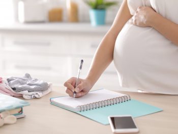 Pregnant woman writing in noteboook