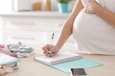 Pregnant woman writing in noteboook