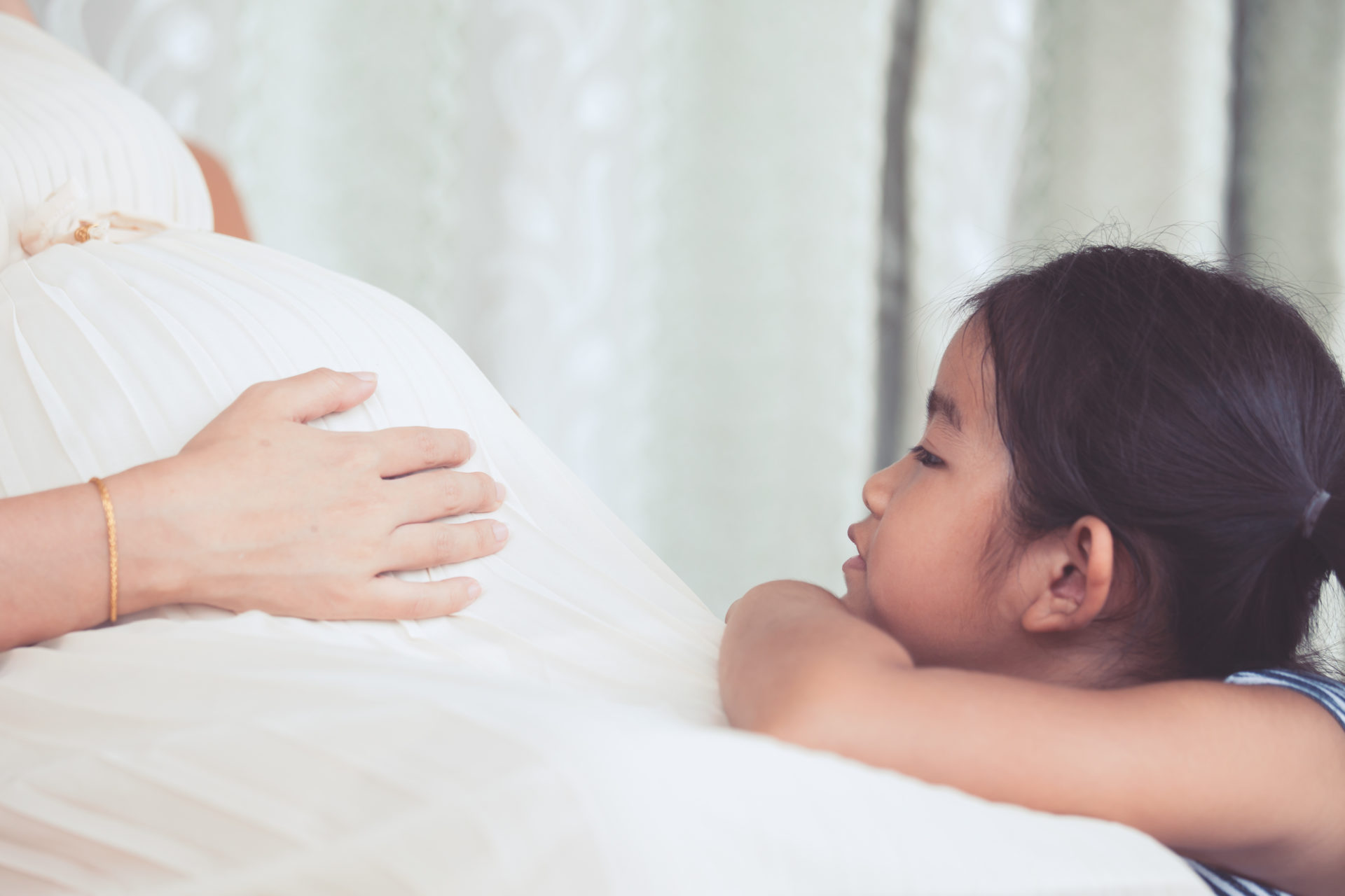 little-girl-looking-at-pregnant-mother's- belly