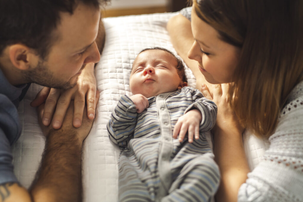 Beautiful-couple-with-newborn-baby-on-bed