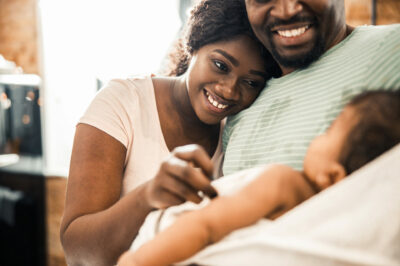 black-mom-leaning-head-on-husbands-shoulder-while-he-holds-newborn-baby