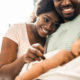 black-mom-leaning-head-on-husbands-shoulder-while-he-holds-newborn-baby
