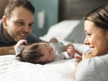 couple-with-newborn-Baby-on-bed