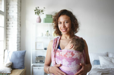 smiling mom with sleeping baby in shoulder sling