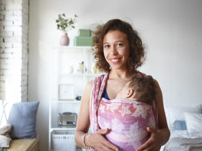 smiling mom with sleeping baby in shoulder sling