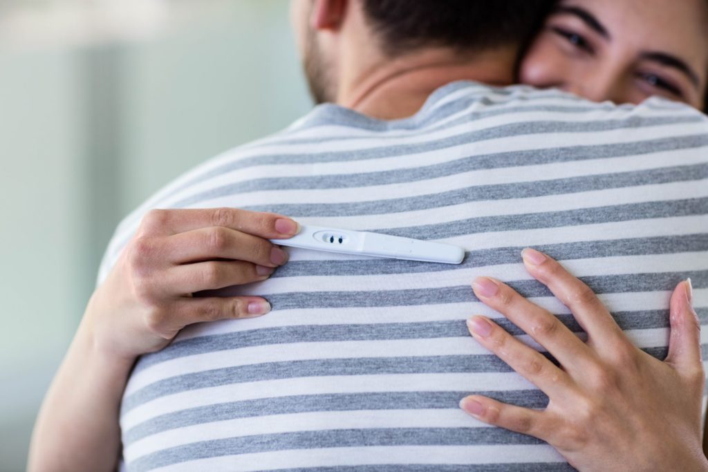 Happy-couple-hugging-with-positive-pregnancy-test