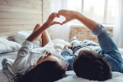 Couple-laying-on-bed-making-heart-shape-with-hands-trying-to-get-pregnant