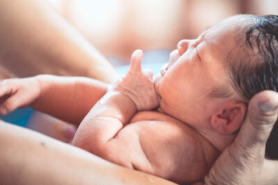 cute-asian-newborn-being-held-by-parent-in-water