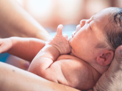 cute-asian-newborn-being-held-by-parent-in-water