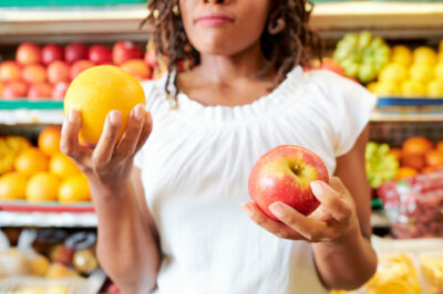 Young-woman-choosing-between-apple-and-orange