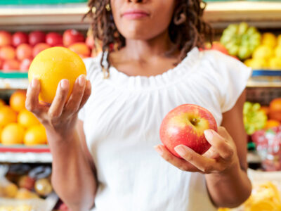 Young-woman-choosing-between-apple-and-orange